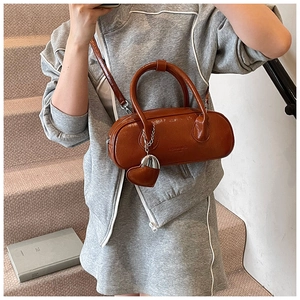 Détail d'un sac à bandoulière en cuir verni marron avec breloque cœur et logo embossé