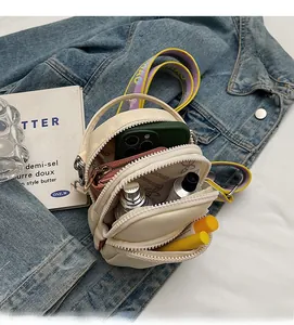Détails intérieurs du sac bandoulière en nylon crème avec trois compartiments zippés