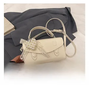 Dettaglio di borsa crema con cuore di perle e fiocchi di pizzo decorativi eleganti