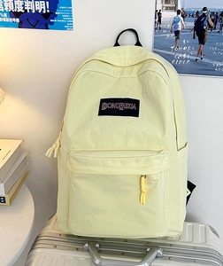 Primer plano de mochila de lona amarilla con compartimentos sobre una maleta plateada