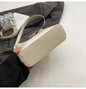 Detail of minimalist beige underarm bag showing clean stitching and silver metal buckle