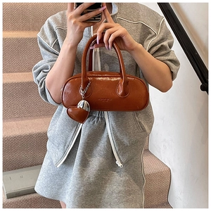 Détail du sac à main en cuir verni orange caramel avec breloque cœur et lettrage mode