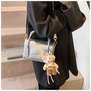 Detail der silbernen Metallic-Umhängetasche mit süßem Teddybär-Anhänger