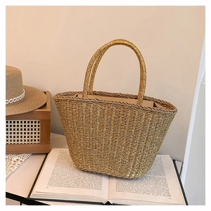 Detail shot of woven straw tote bag with ring handles on a minimalist book setup