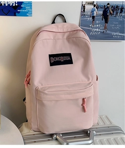 Detalle de mochila de lona rosa claro con bolsillo frontal y etiqueta de marca