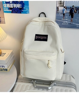 Vista detallada de la mochila de nailon minimalista crema sobre una maleta de viaje