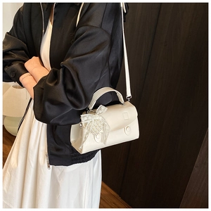 Dettaglio della mini borsa bianca con fiocco di pizzo e perle su una finitura in pelle liscia