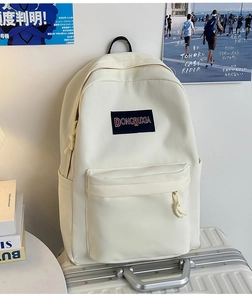 Primer plano de una mochila de lona blanco crema con bordado sobre una maleta plateada