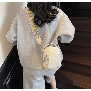 Détail d'un sac à bandoulière crème avec trois compartiments zippés et une sangle large