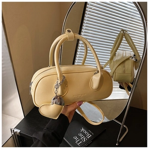Détail d'un petit sac bowling jaune avec pendentif cœur et poignées en cuir