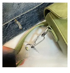 Detail of silver metal hook and fine stitching on a grass green crossbody bag strap