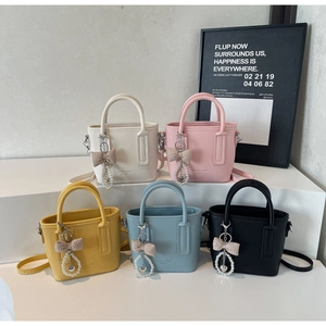 Detail of mini leather tote bags in five colors with pearl charms on tiered display