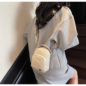 Sac bandoulière en nylon beige crème avec sangle rayée dans un style urbain épuré