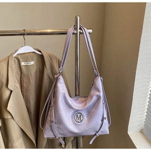 Détail du grand sac cabas en cuir lilas avec logo M métallique et cordons réglables sur les côtés