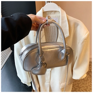 Détail montrant la texture cuir argenté et le charme en cœur du sac bowling chic