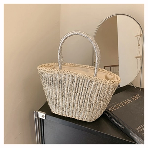 Detail of hand-woven straw tote with shimmering silver threads and metallic handles