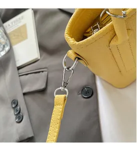 Close-up of bright yellow litchi grain leather bucket bag with silver metal hooks