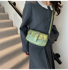 Model wearing a light green PU leather shoulder bag with metallic buckle and zip details