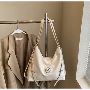 Détail du sac cabas en cuir blanc crème avec texture plissée et détail du logo M doré