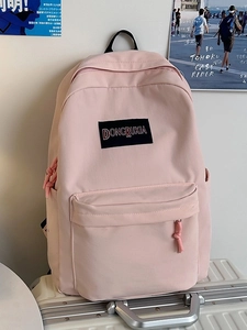 Mochila de nailon rosa de diseño minimalista y gran capacidad sobre una maleta