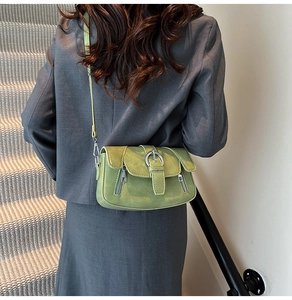 Avocado green crossbody bag with metal buckle shown on model in a minimalist setting