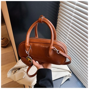 Détail d'un sac bowling marron vintage avec doubles anses et breloque coeur à la mode