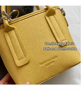 Close-up of yellow lychee grain leather handbag with silver rings and metal hardware