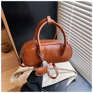 Détail d'un sac bowling marron vintage avec pendentif cœur et texture en cuir brillant