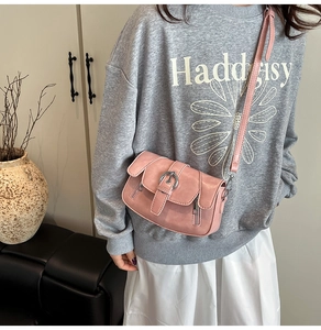 Pink vintage leather crossbody bag with metal buckle shown in a lifestyle setting