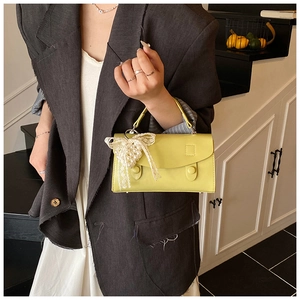 Dettaglio della borsa a mano in pelle giallo lime con ciondolo a fiocco in pizzo e perle
