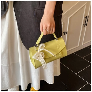Dettagli della mini borsa verde lime con fiocco in pizzo bianco e ciondoli di perle
