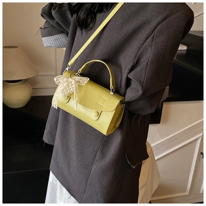 Dettaglio borsa verde lime con fiocco in pizzo bianco e ciondolo di perle decorative