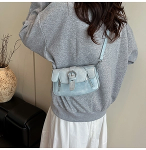 Detail view of light blue retro crossbody bag with vintage washed texture and metal buckle