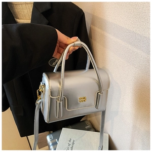 Details der silbernen Metallic-Handtasche mit goldenem Logo und polierter Textur