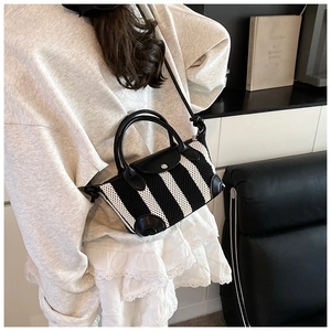 Dettaglio di una mini borsa in maglia a righe bianche e nere e manici in pelle
