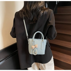 Detail of light blue bucket bag with heart pendant and bow on vintage wood stairs