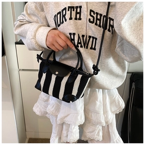 Dettaglio della mini borsa a righe con accenti in pelle indossata a tracolla qui