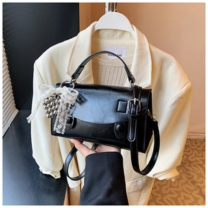 Dettagli di una borsa in pelle nera lucida con ciondolo in pizzo elegante