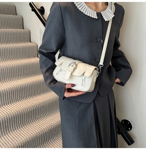 Detail of cream vintage crossbody bag featuring metal buckle and side zipper accents