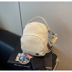 Détail du sac bandoulière en nylon crème avec double zip et large sangle en jacquard
