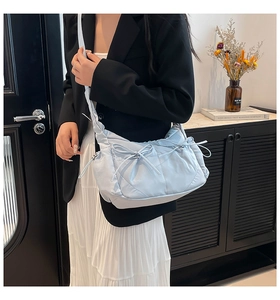 Détail d'un sac bandoulière matelassé en nylon bleu clair avec des nœuds coulissants