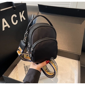 Détail du sac bandoulière en nylon noir avec sangle jacquard et logo métallique