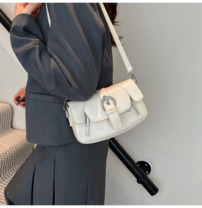 Close-up of a cream white PU leather crossbody bag with oversized silver buckle detail