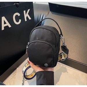 Détail du mini sac bandoulière en nylon noir avec bandoulière ethnique colorée et zip