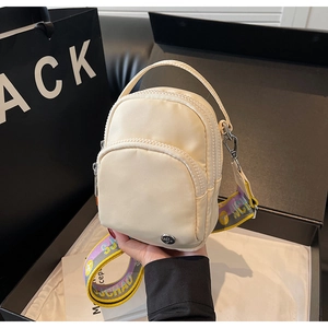 Détail d'un sac bandoulière beige en nylon avec double zip et large sangle colorée en boîte
