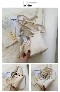 Detail of white bucket bag with pebble leather texture and silk scarf wrapped on handle