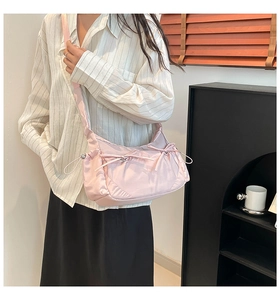 Détail du sac bandoulière en nylon rose avec nœud décoratif et large bandoulière réglable