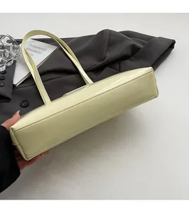 Detailed view of cream yellow patent leather bag base with fine stitching and smooth finish
