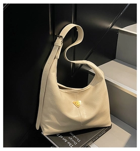 Detail of cream pleated leather underarm bag with gold triangle emblem and texture