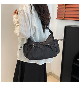Détail du sac à bandoulière en nylon noir avec cordons de serrage et anneaux métalliques